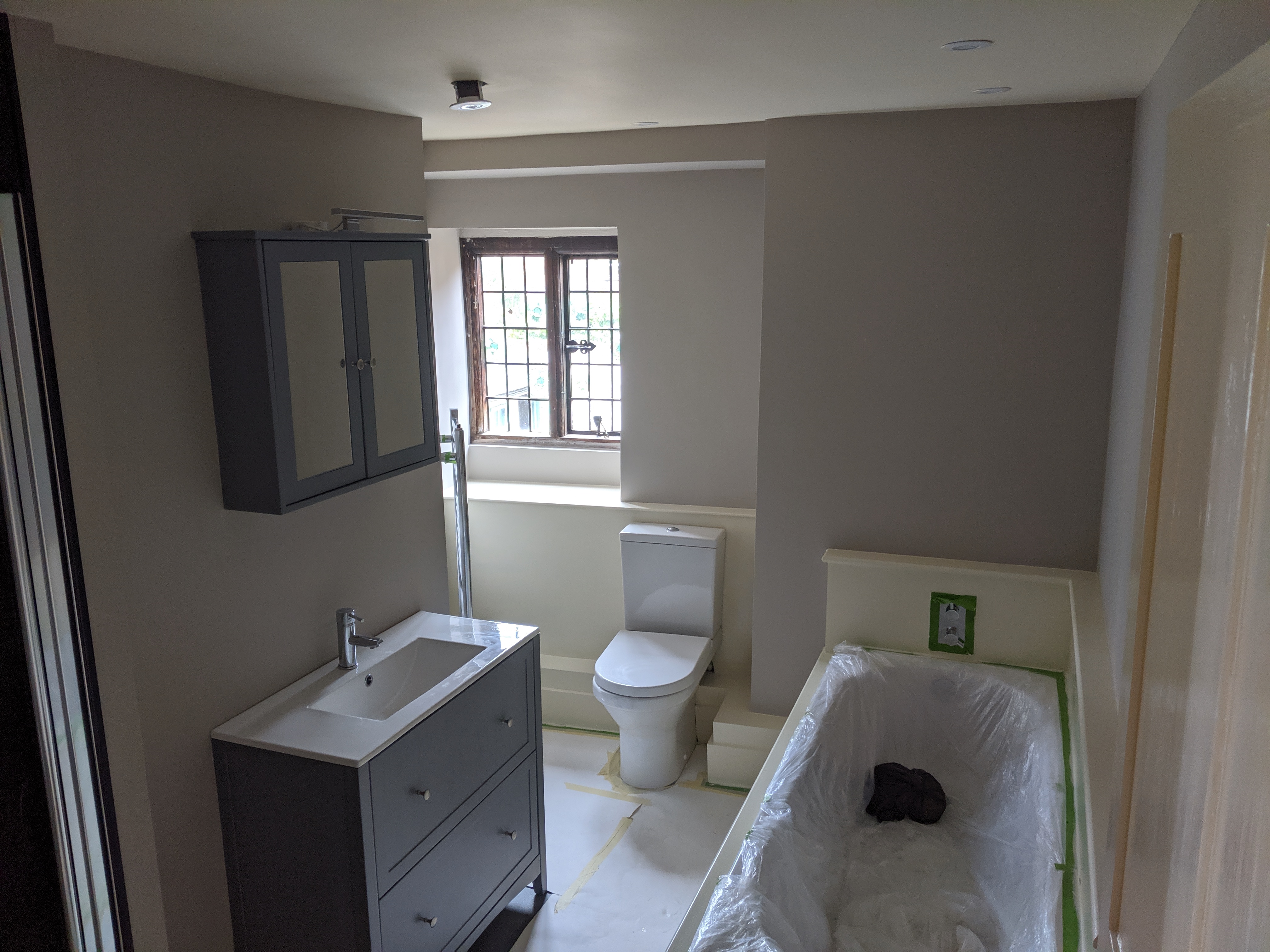 Bathroom with grey vanity, taupe painted walls and period leaded window