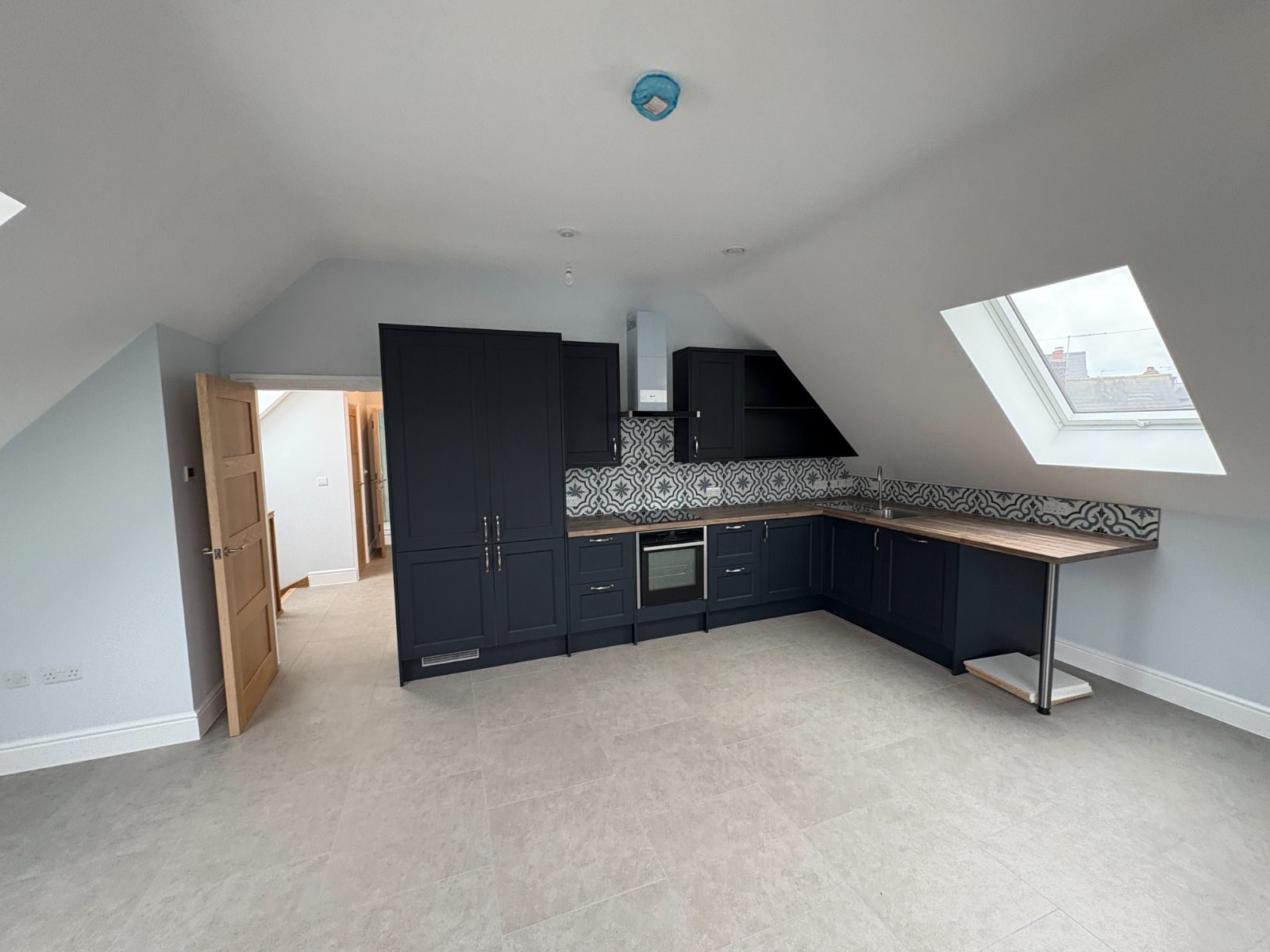 Navy shaker kitchen with patterned tile splashback in a loft conversion