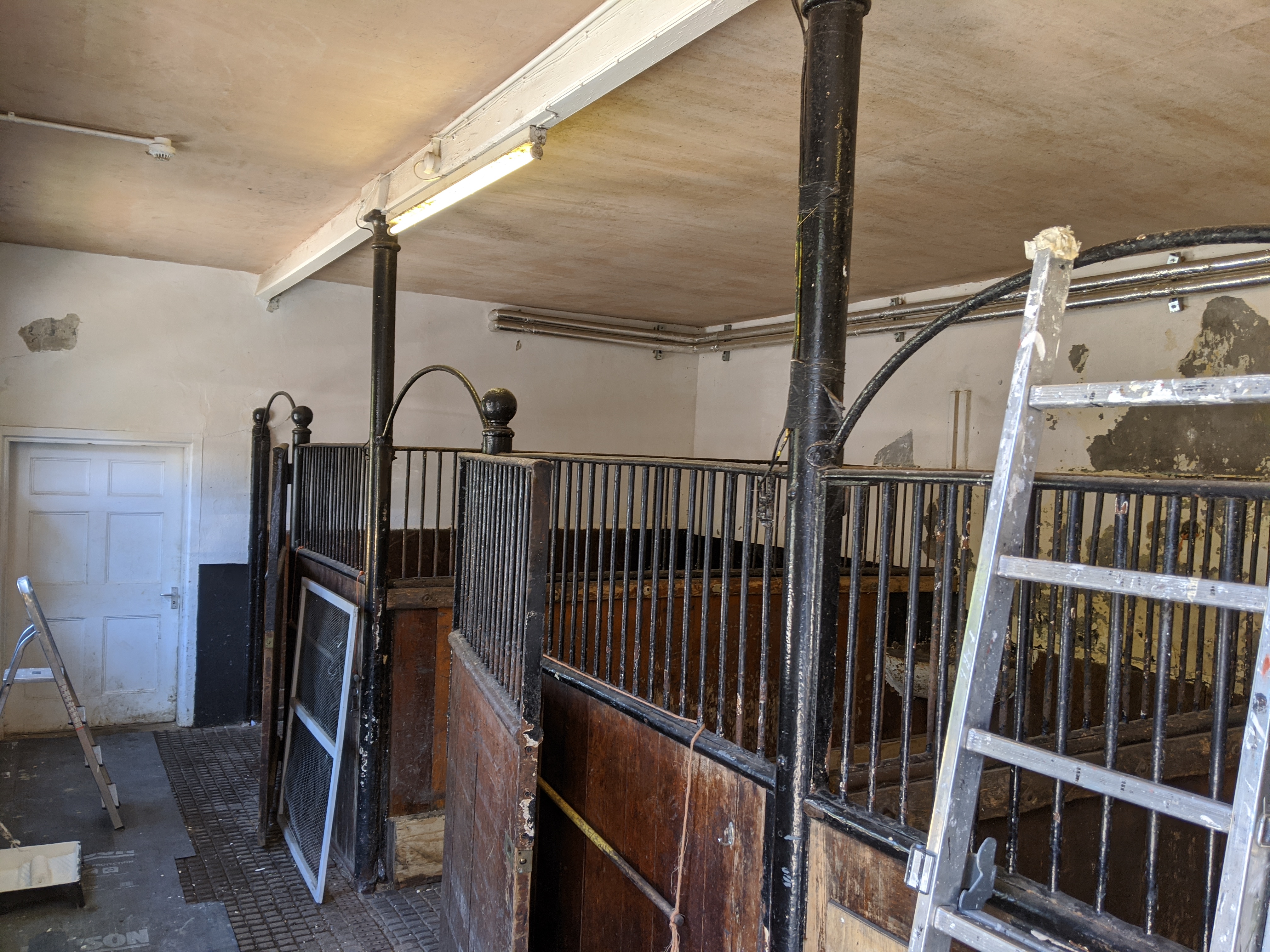 Horse stalls before renovation — iron railings and peeling paint