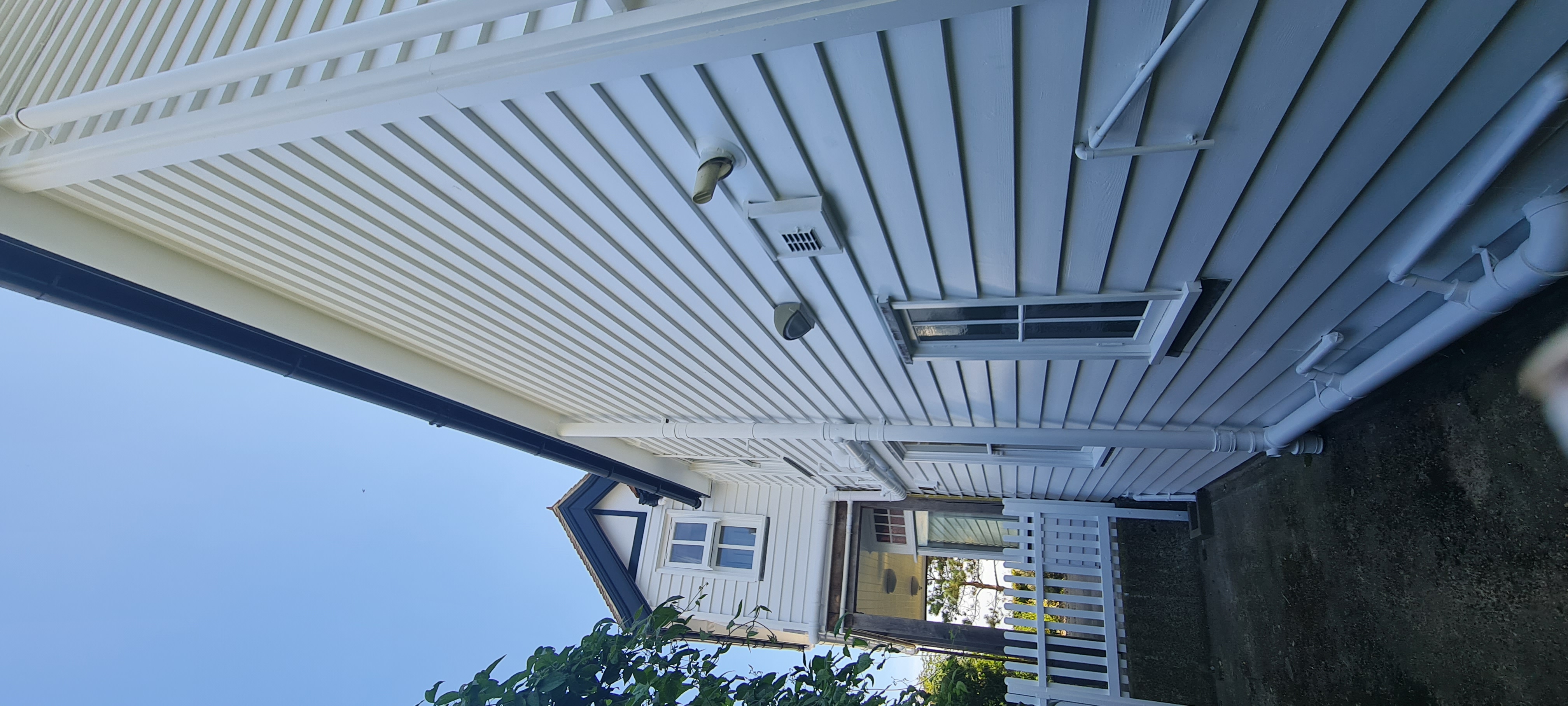 White painted seafront weatherboard house against blue sky