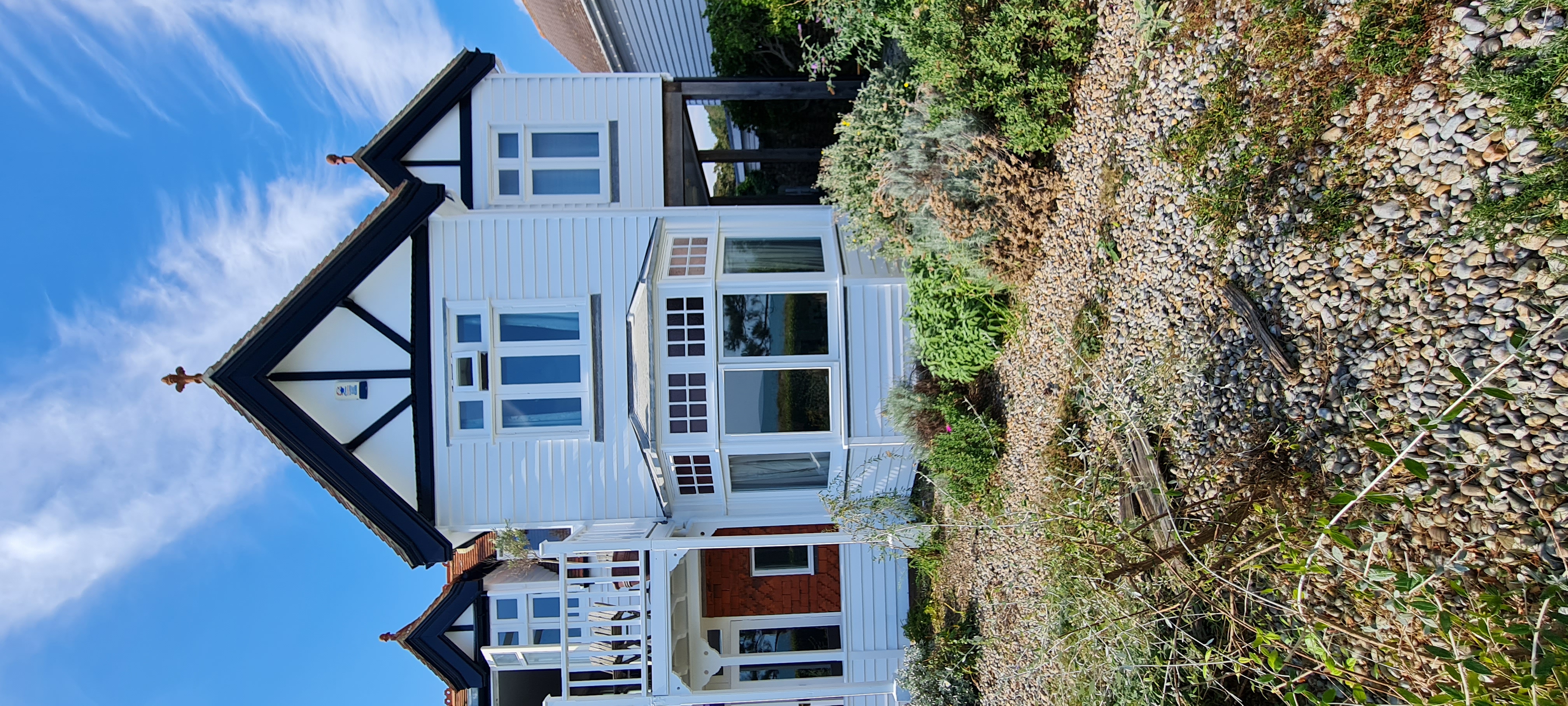 Seafront white rendered house with freshly painted bay window and railings