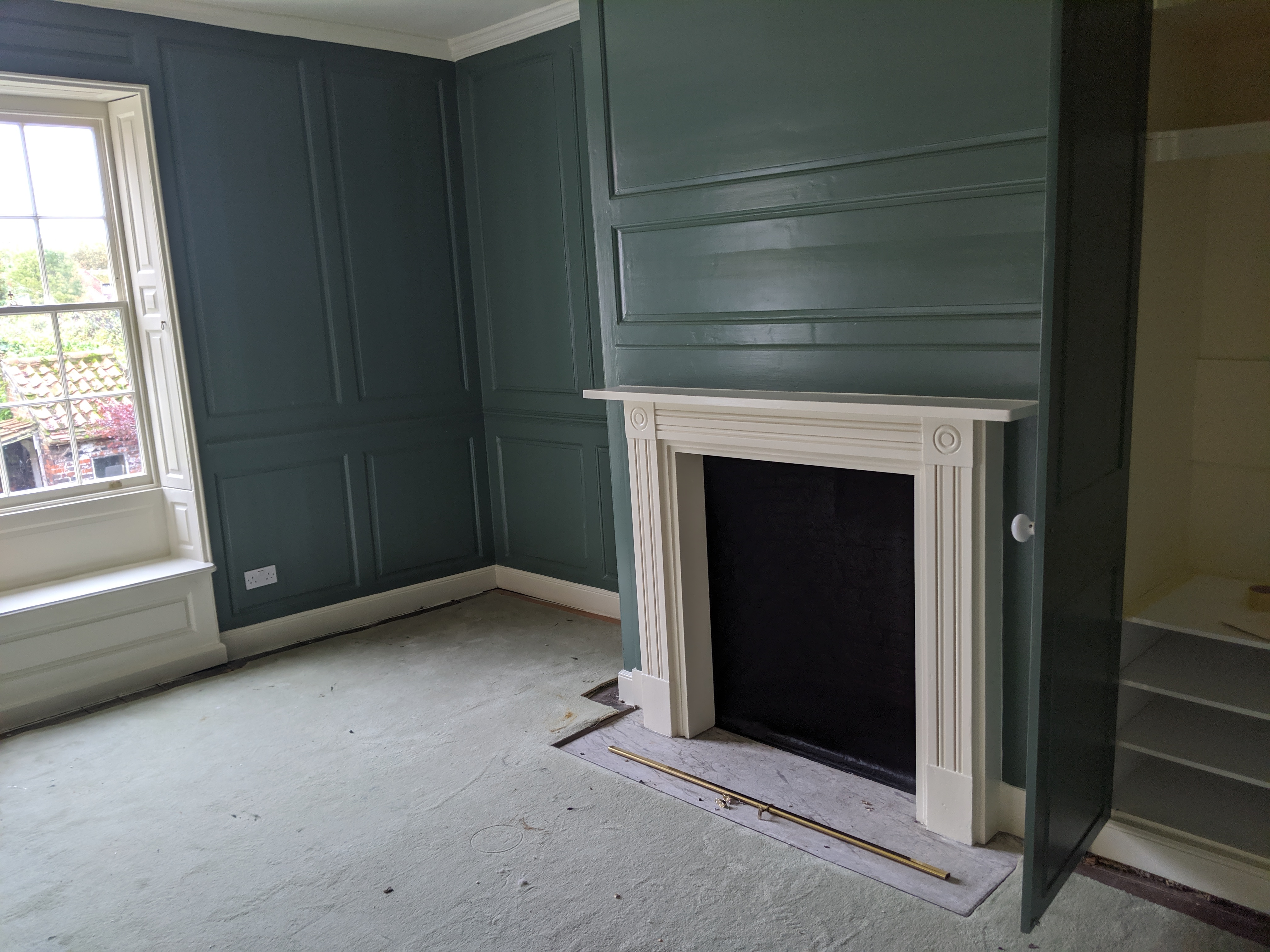 Teal painted panelled room with white period fireplace surround