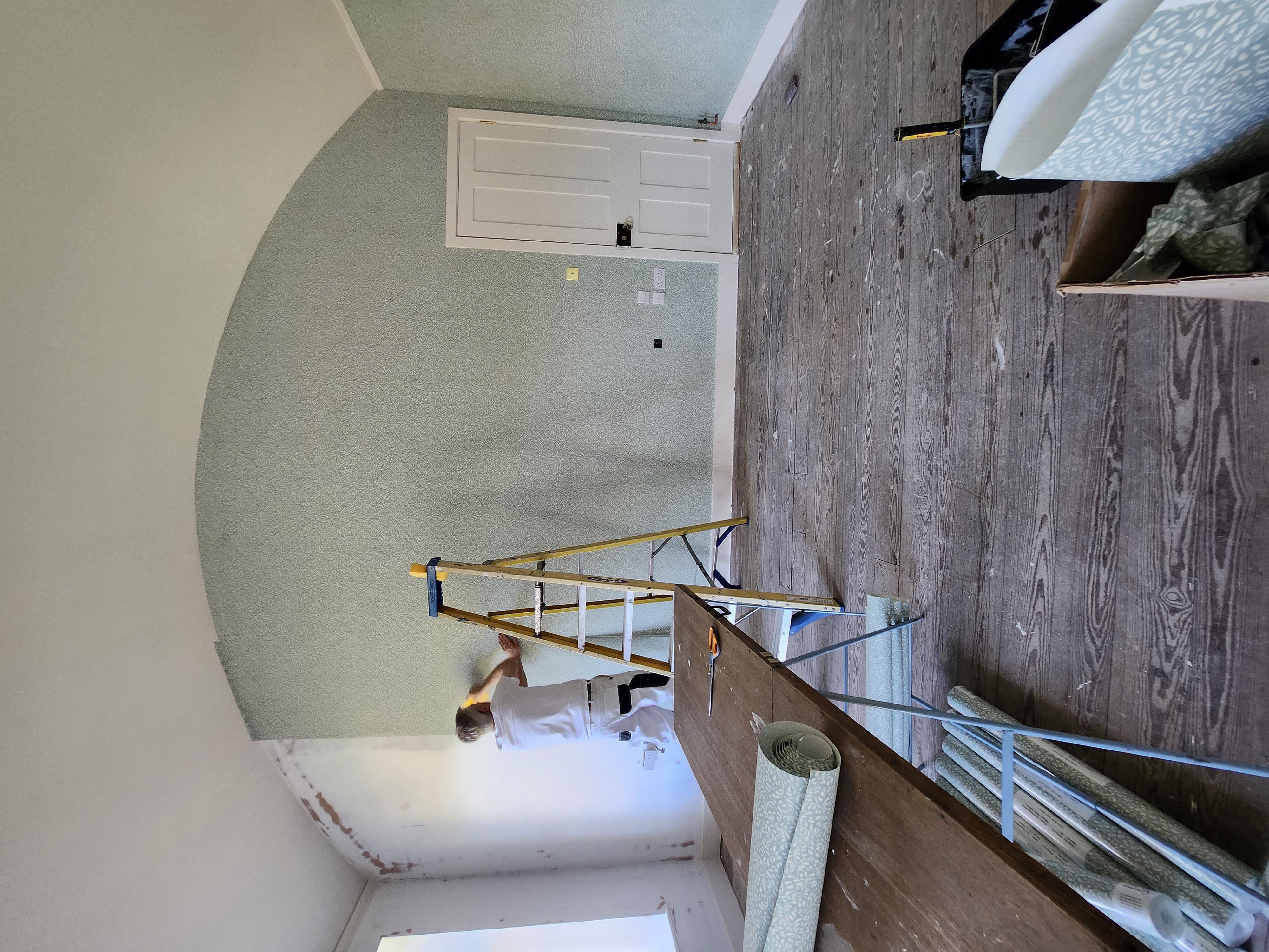 Painter decorating an arched feature wall in sage green