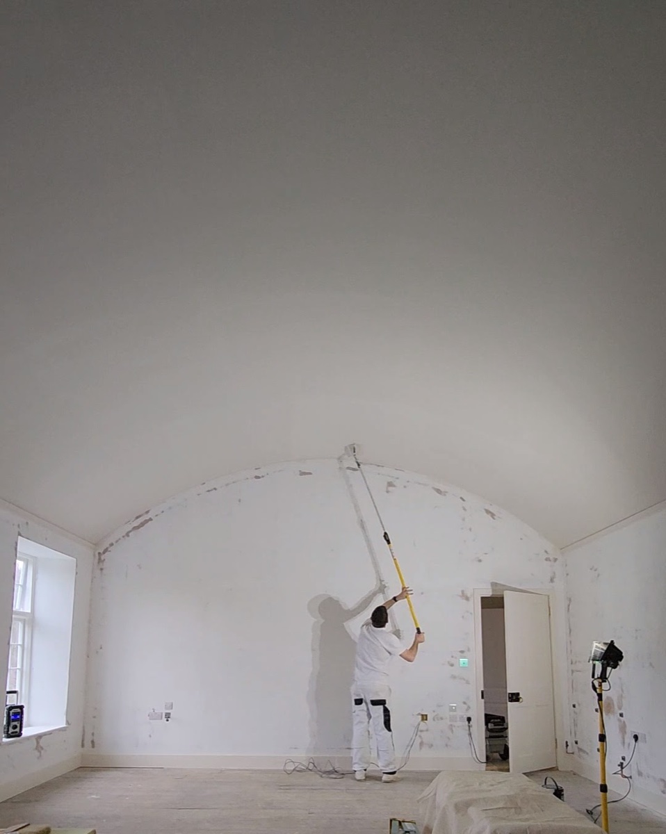 Painter working on vaulted arch ceiling with roller