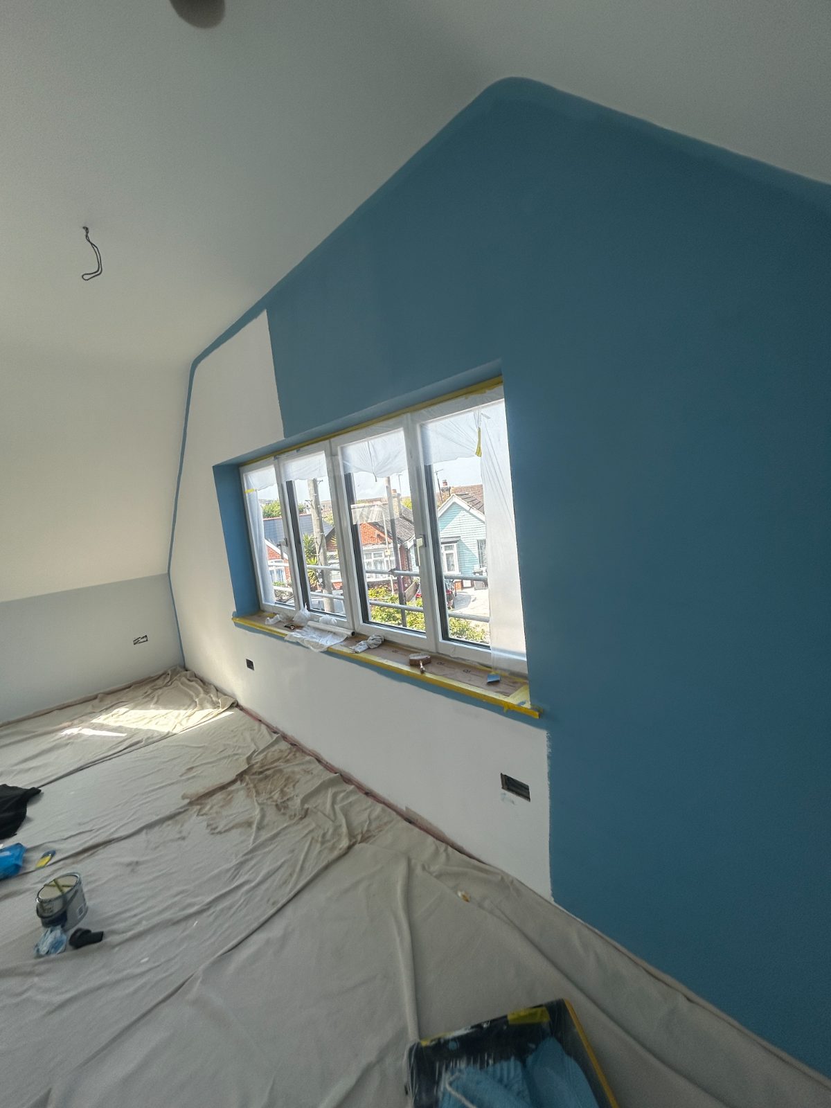 Loft bedroom with a blue painted gable wall and a leaded window
