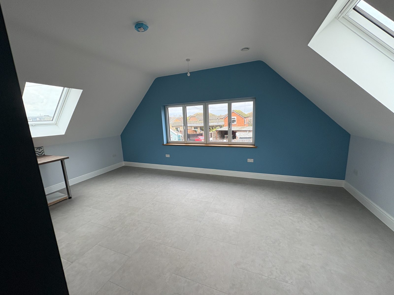 Loft bedroom with a blue painted feature gable wall and skylights