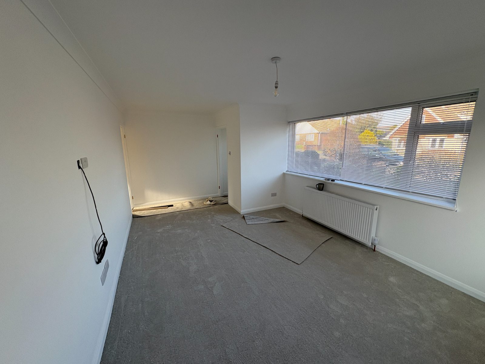 Bright finished reception room with new carpet and a large window