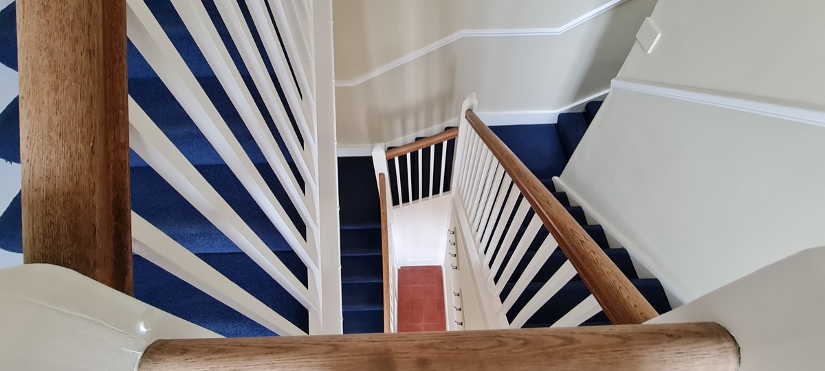 Staircase with navy blue carpet and white painted balustrade