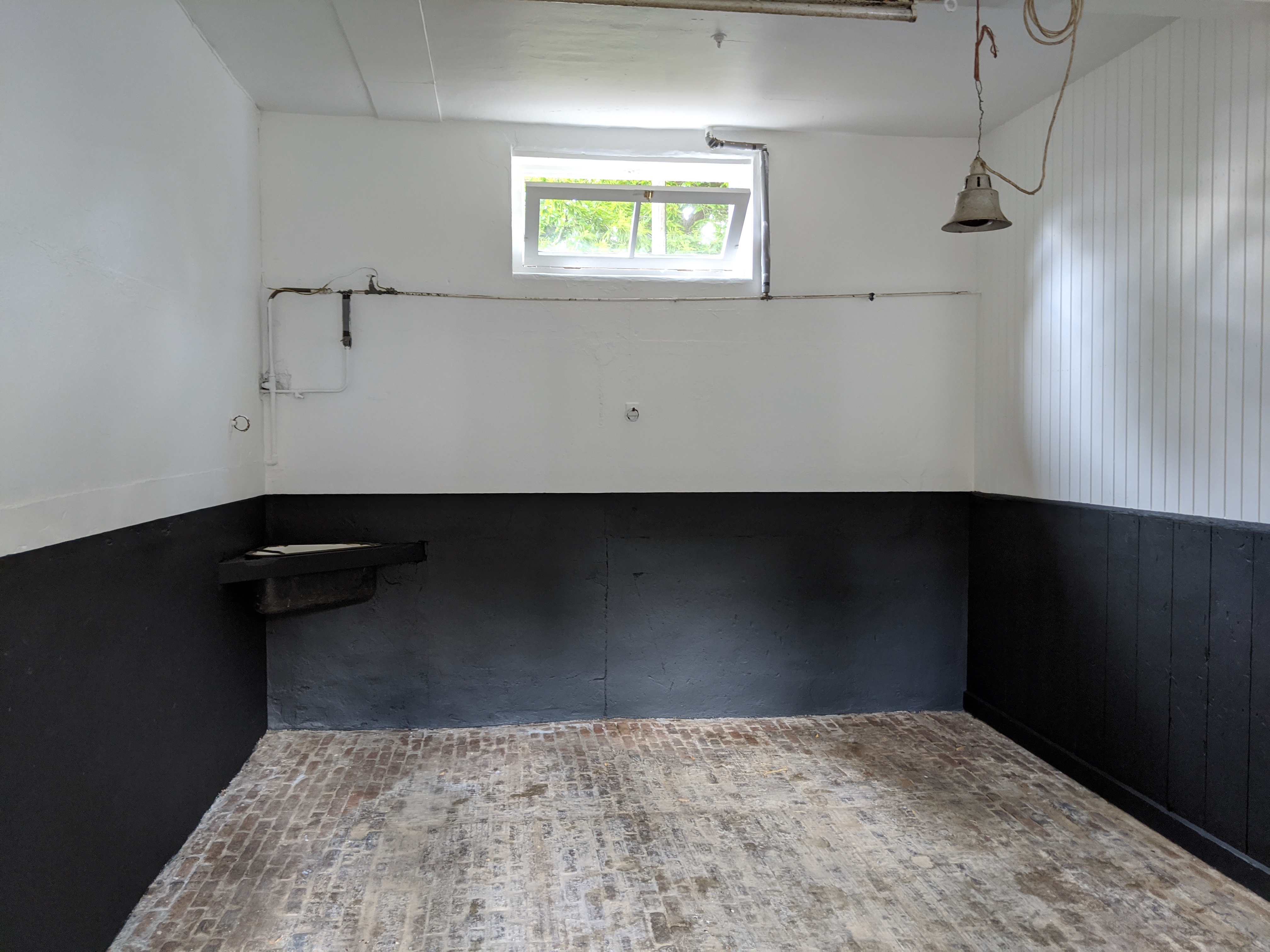 Outhouse interior with painted brick — black lower half, white upper half